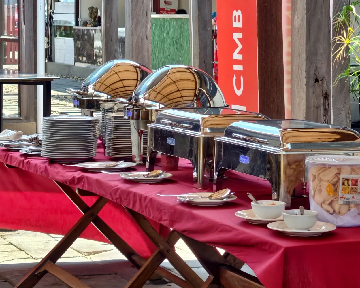 Meja prasmanan katering Ocean's Resto dengan chafing dish dan tumpukan piring siap saji