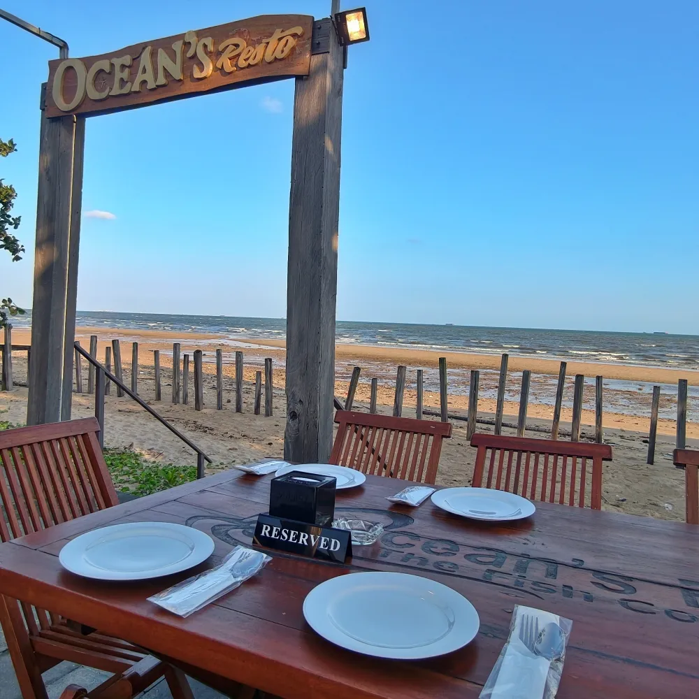 Meja bertanda Reserved menghadap gerbang kayu Ocean's Resto dan pantai Balikpapan